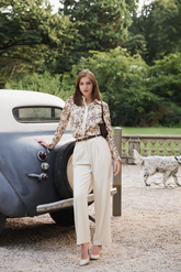 a lady in a floral printed shirt and a pair of white pants